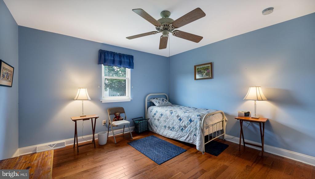 Bedroom with blue walls, a single bed, hardwood floors, and a ceiling fan.