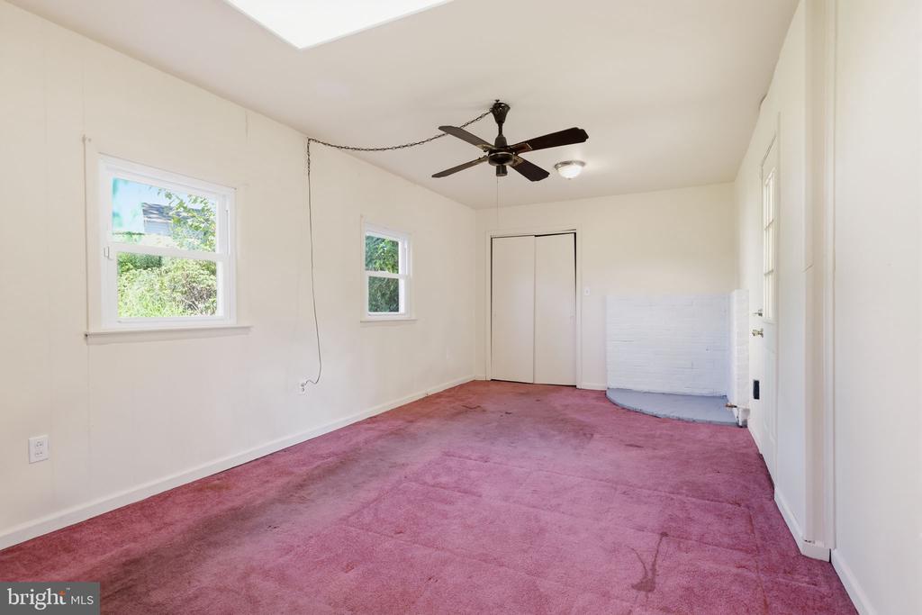 Empty bedroom with pink carpet, two windows, a closet, and a ceiling fan.