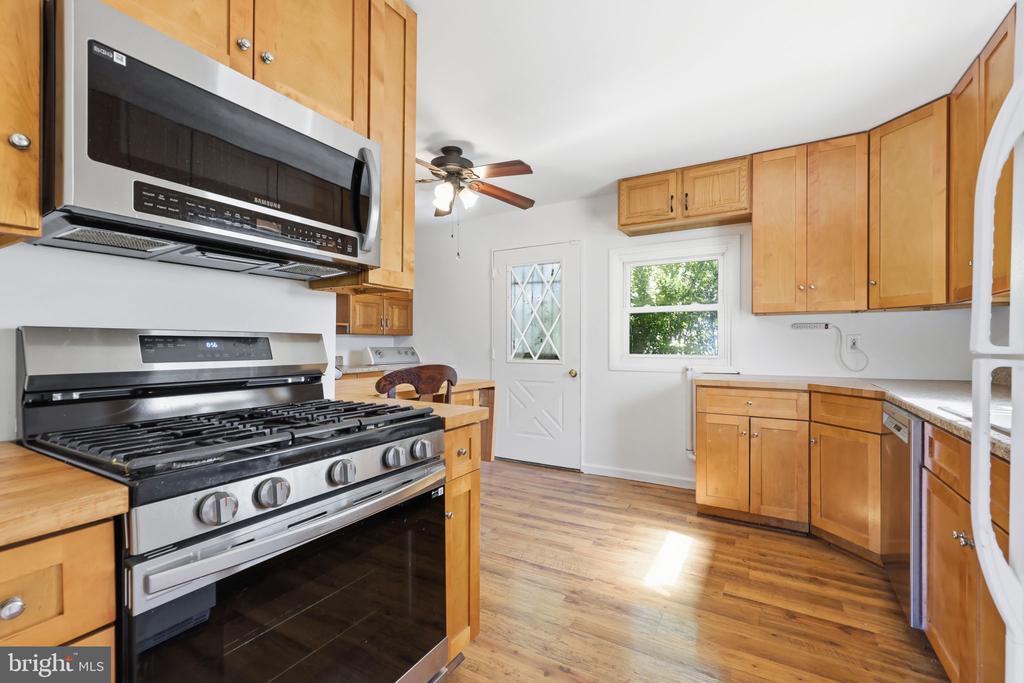 Kitchen with wood cabinets, a stainless steel range and microwave, and hardwood floors.