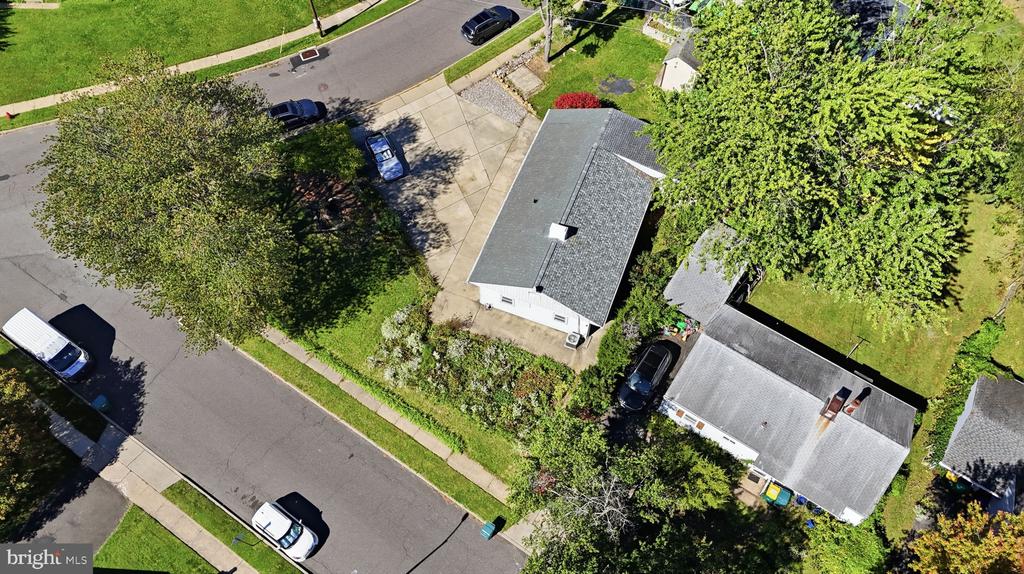 Aerial view of a single-story home among mature trees beside a residential street.
