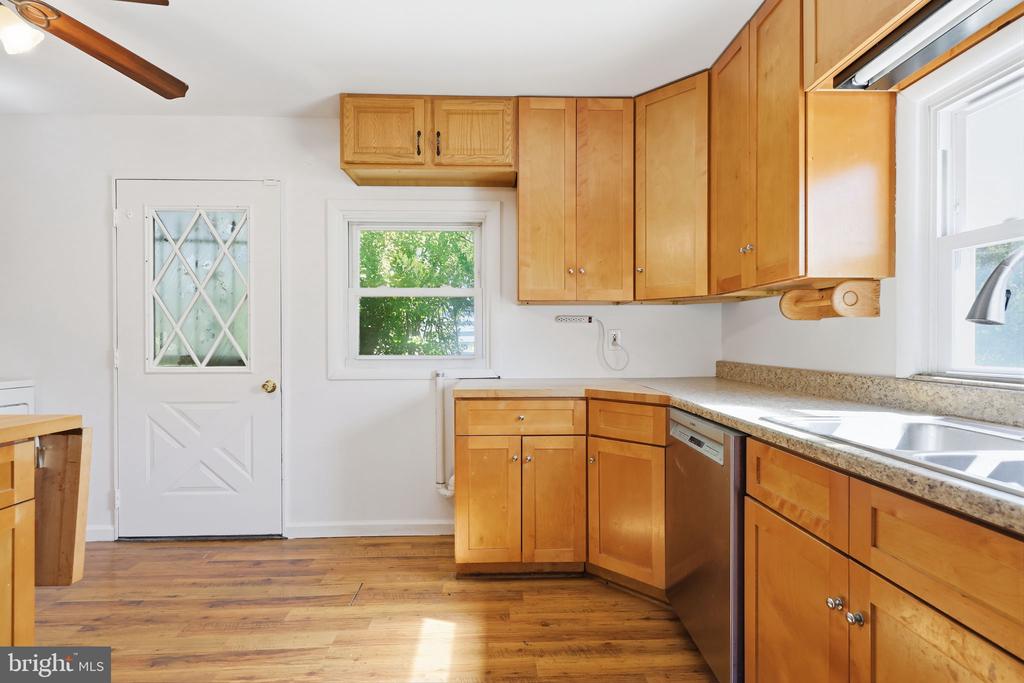 Kitchen with honey-toned cabinets, speckled counters, a double sink, and hardwood floors.