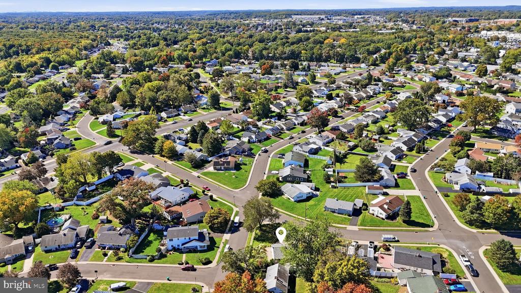 Aerial view of a tree-lined residential neighborhood with a map pin marking the property.