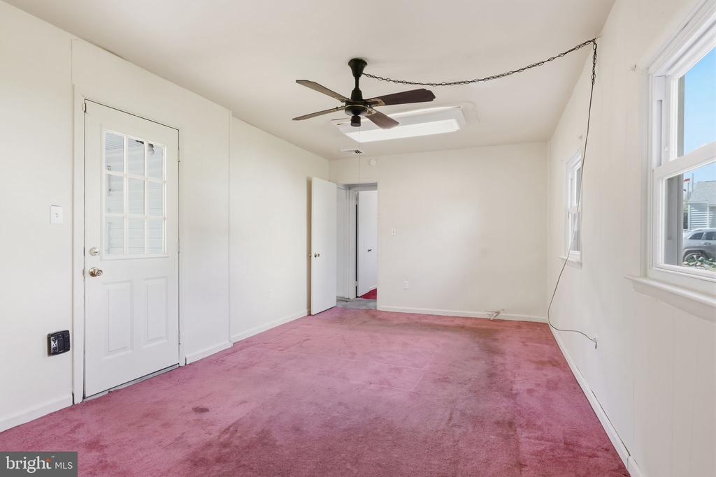 Empty room with pink carpet, a ceiling fan, an exterior door, and windows.