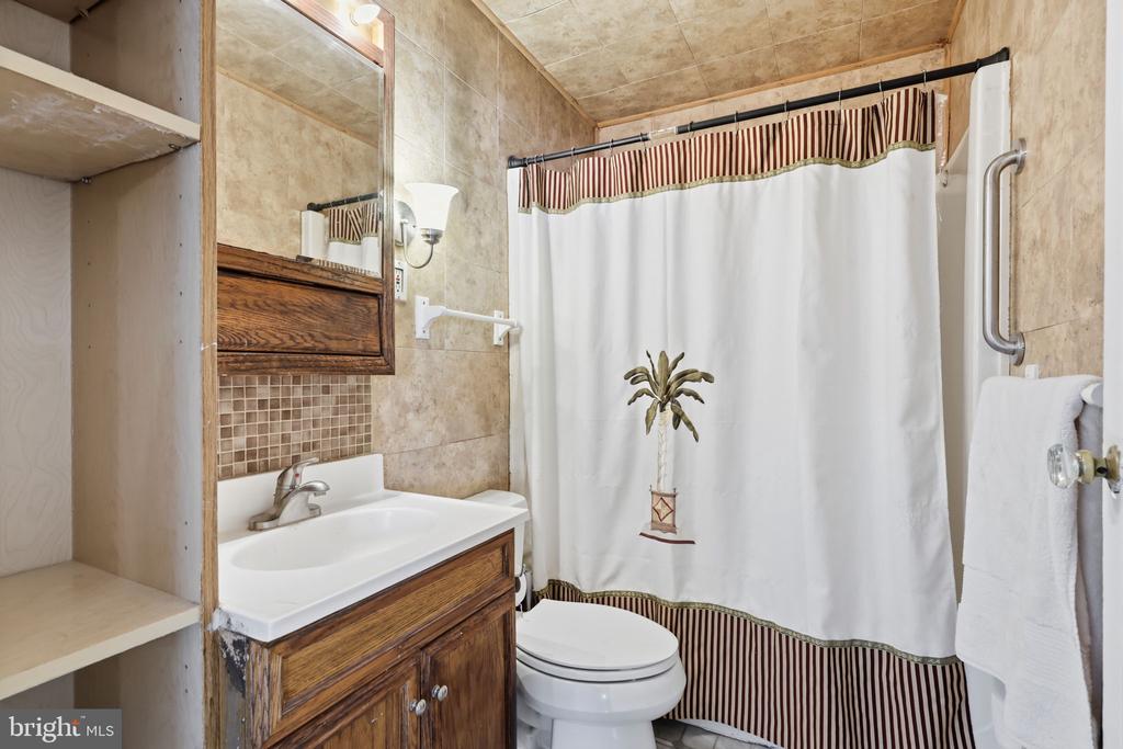 Bathroom with a wood vanity, mirrored cabinet, and white shower curtain with striped trim.