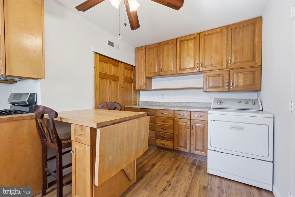 Kitchen with extensive honey-colored wood cabinetry, a central island, and a white laundry appliance.