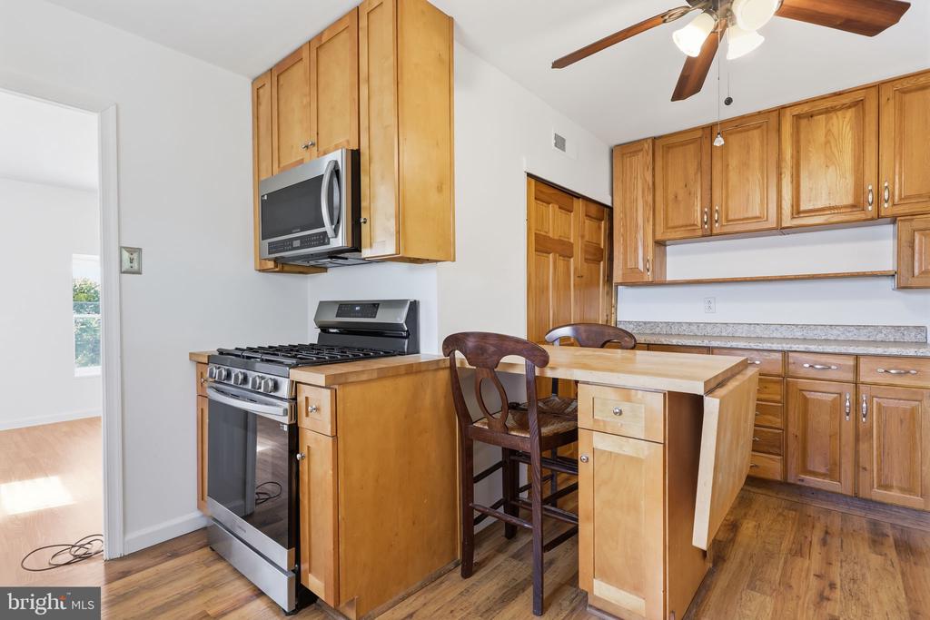 Kitchen with honey-colored cabinets, stainless steel appliances, granite counters, and a breakfast bar.