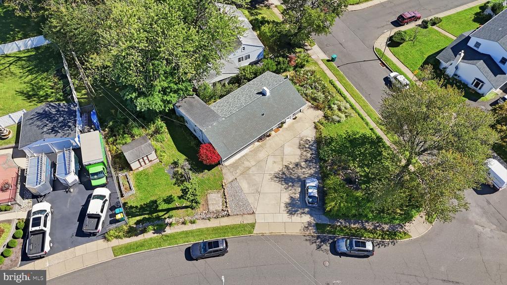 Aerial view of a single-story home with a broad driveway and mature trees.