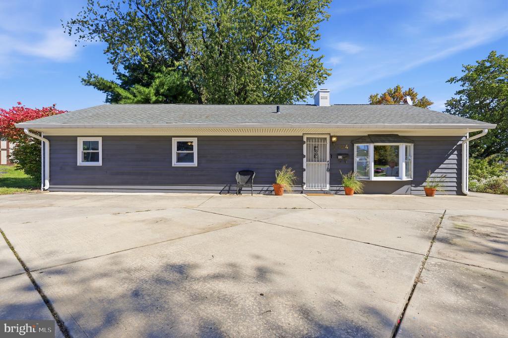 Single-story gray house with white trim, a bay window, and a wide concrete driveway.