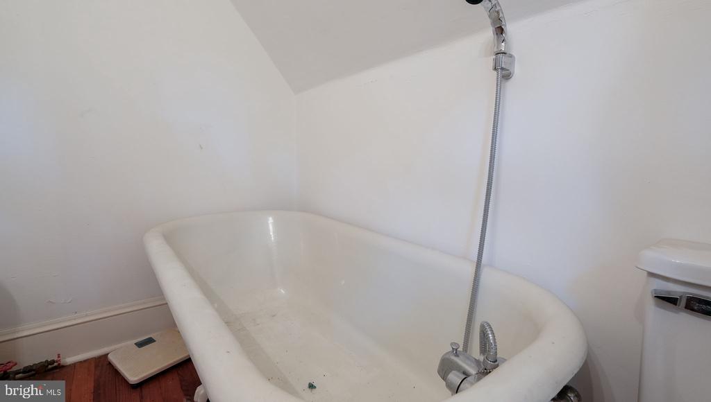 White bathtub with handheld shower hose in a bathroom.