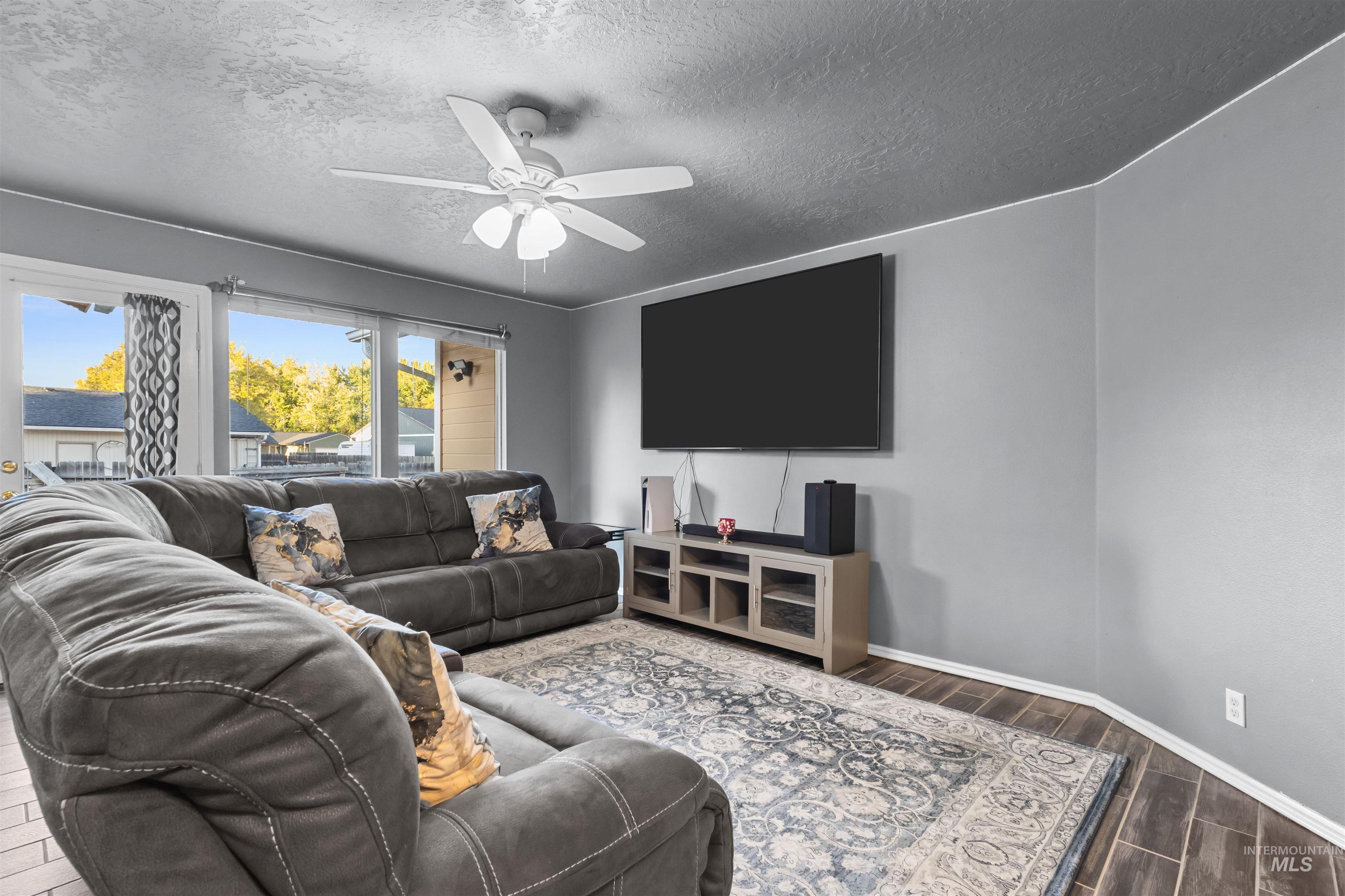 Furnished living room with a large sectional, patterned rug, and wall-mounted television.