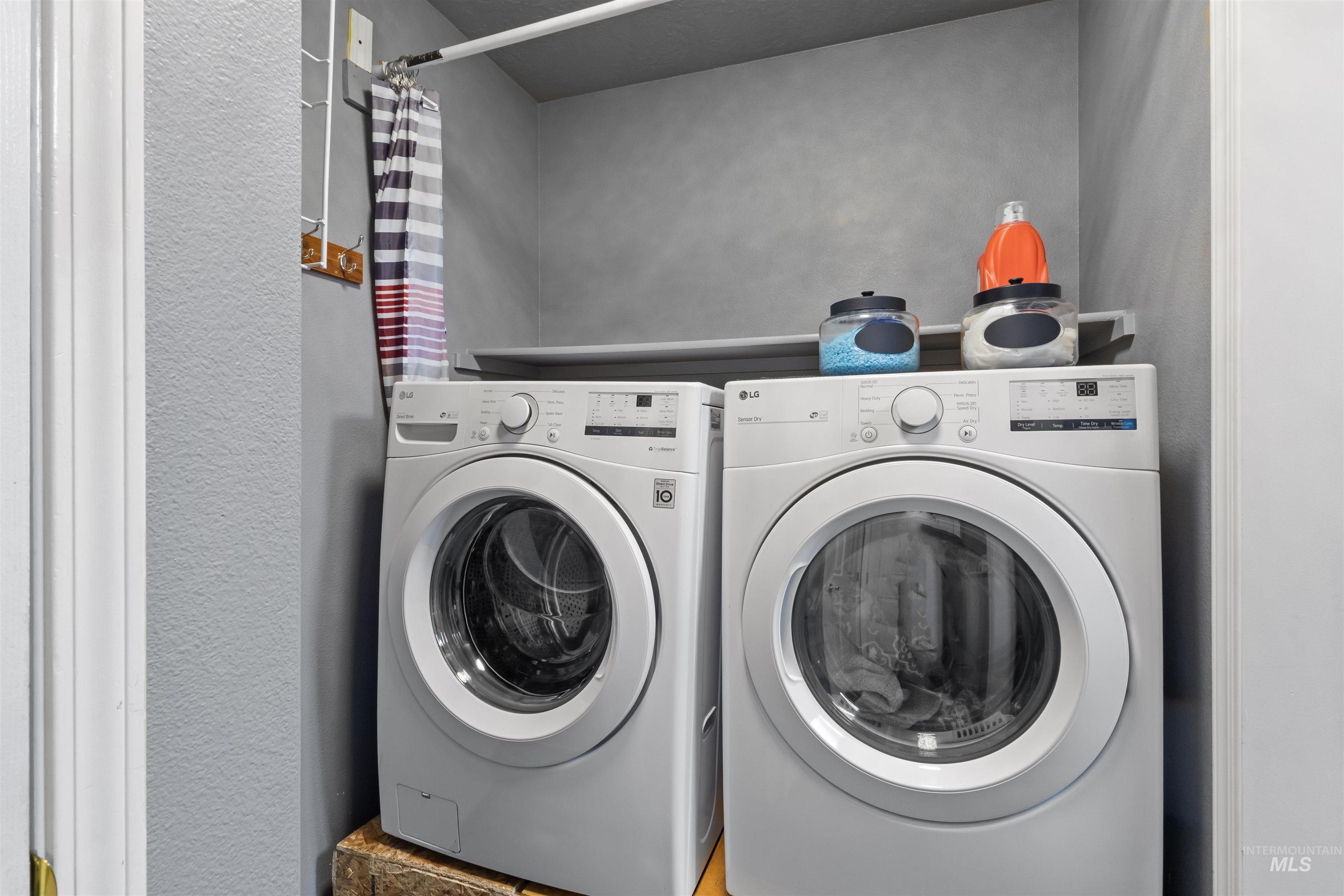 Laundry room with matching front-loading washer and dryer beneath a shelf.