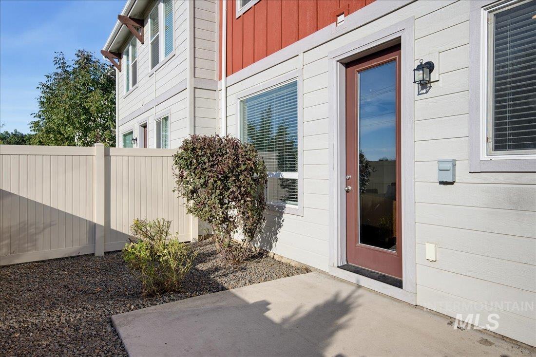 Home exterior with a glass-panel door opening onto a small concrete patio beside a privacy fence.