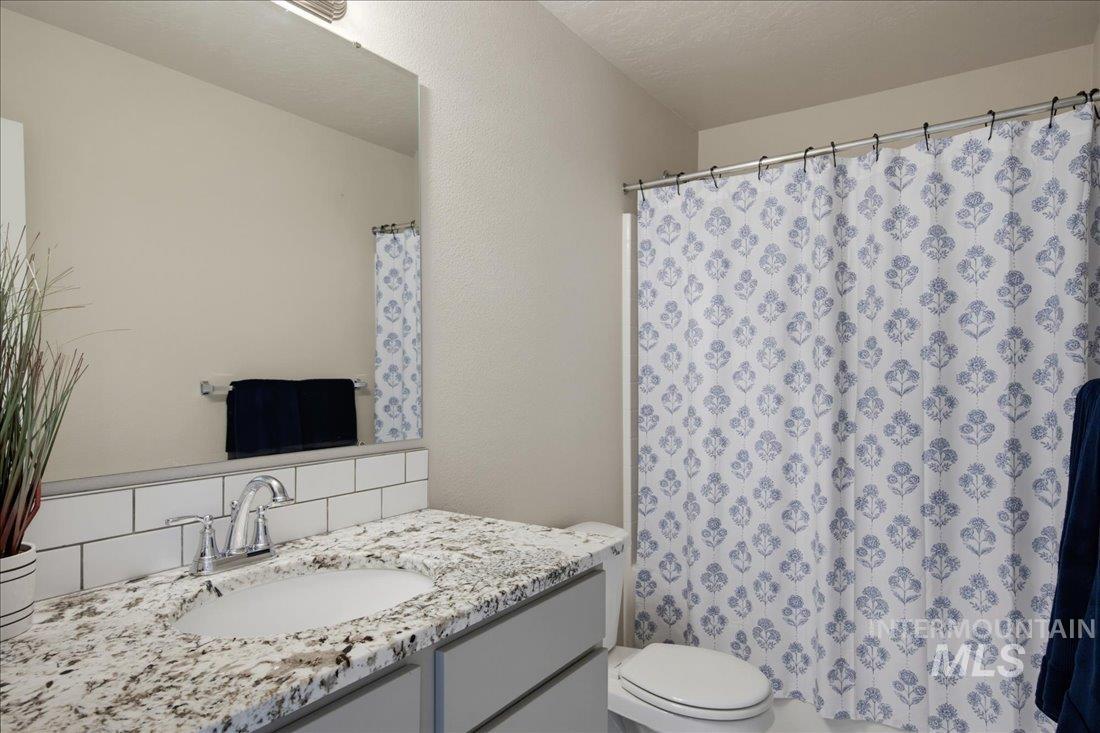 Bathroom with a granite vanity, large mirror, and blue floral shower curtain.
