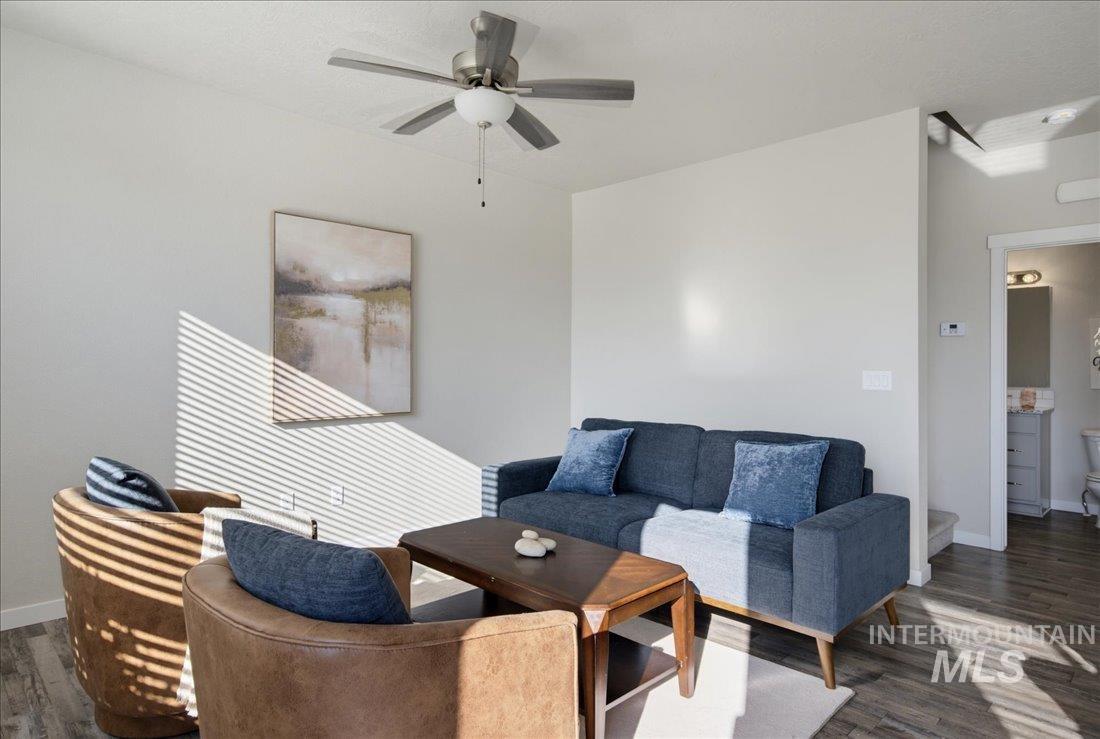 Living room with a blue sofa, brown armchairs, wooden coffee table, and sunlight casting striped shadows.