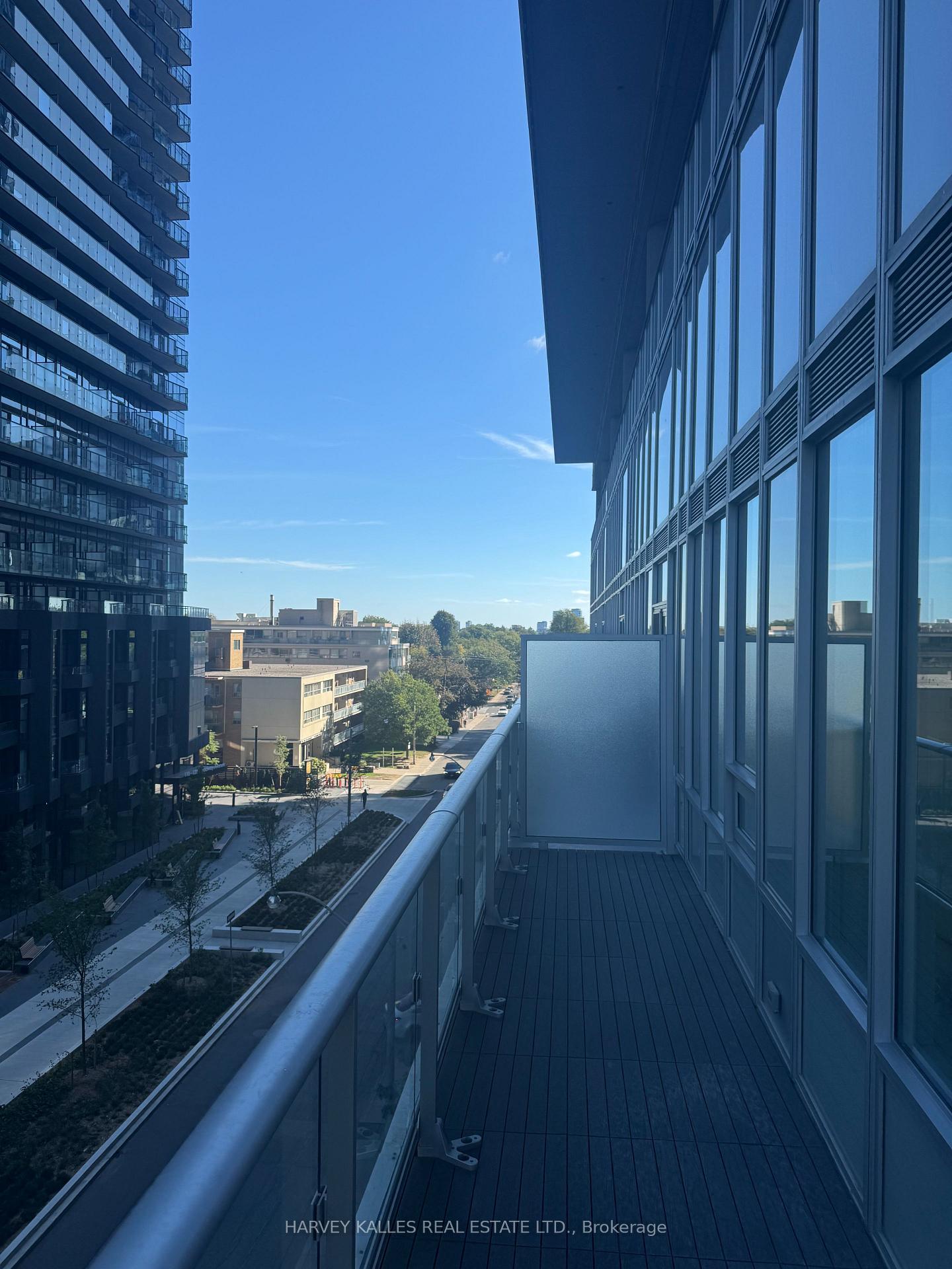 Condominium balcony overlooking a landscaped walkway and neighboring high-rise buildings.
