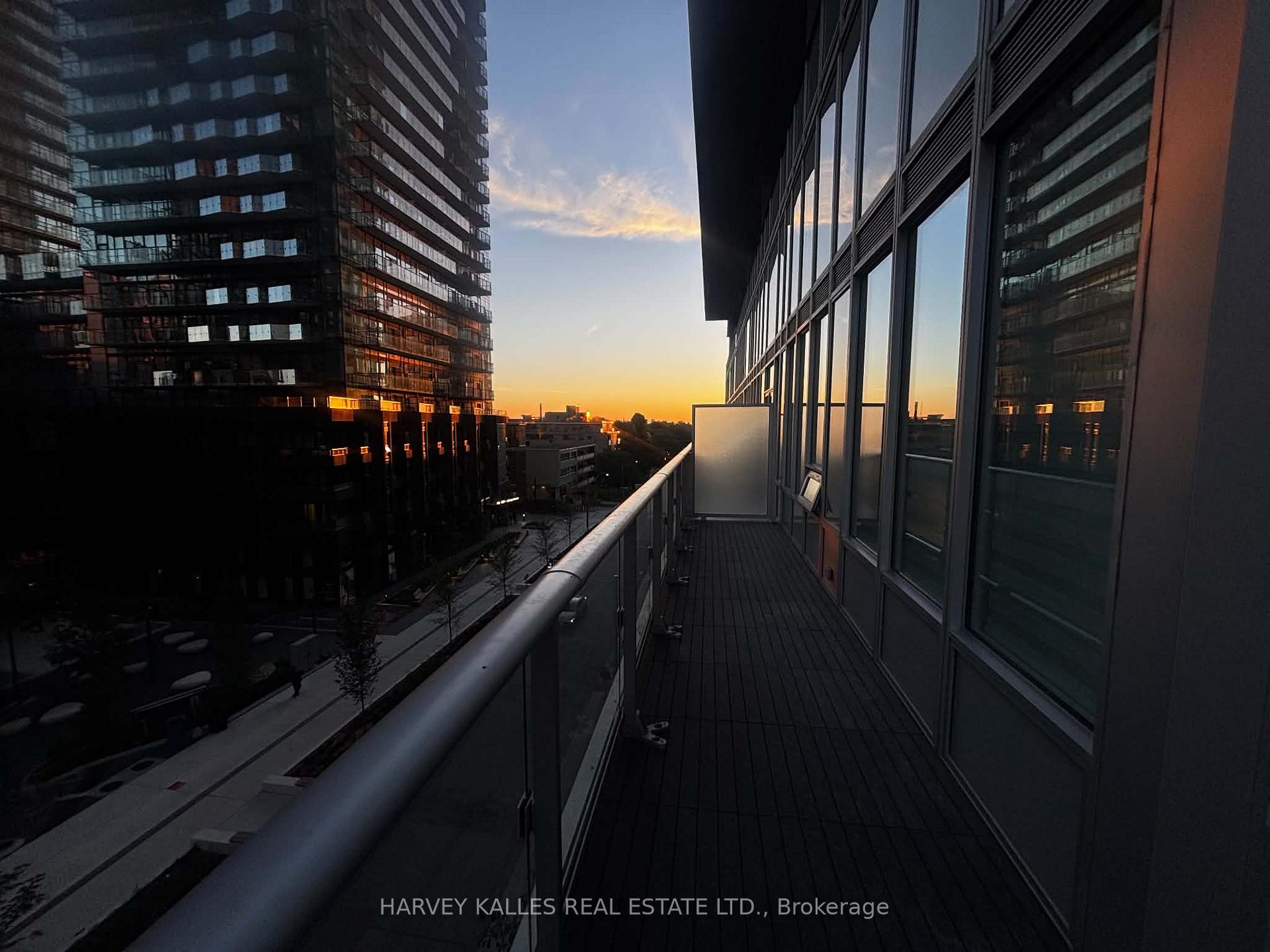 Condo balcony with glass railing and high-rise views at sunset.