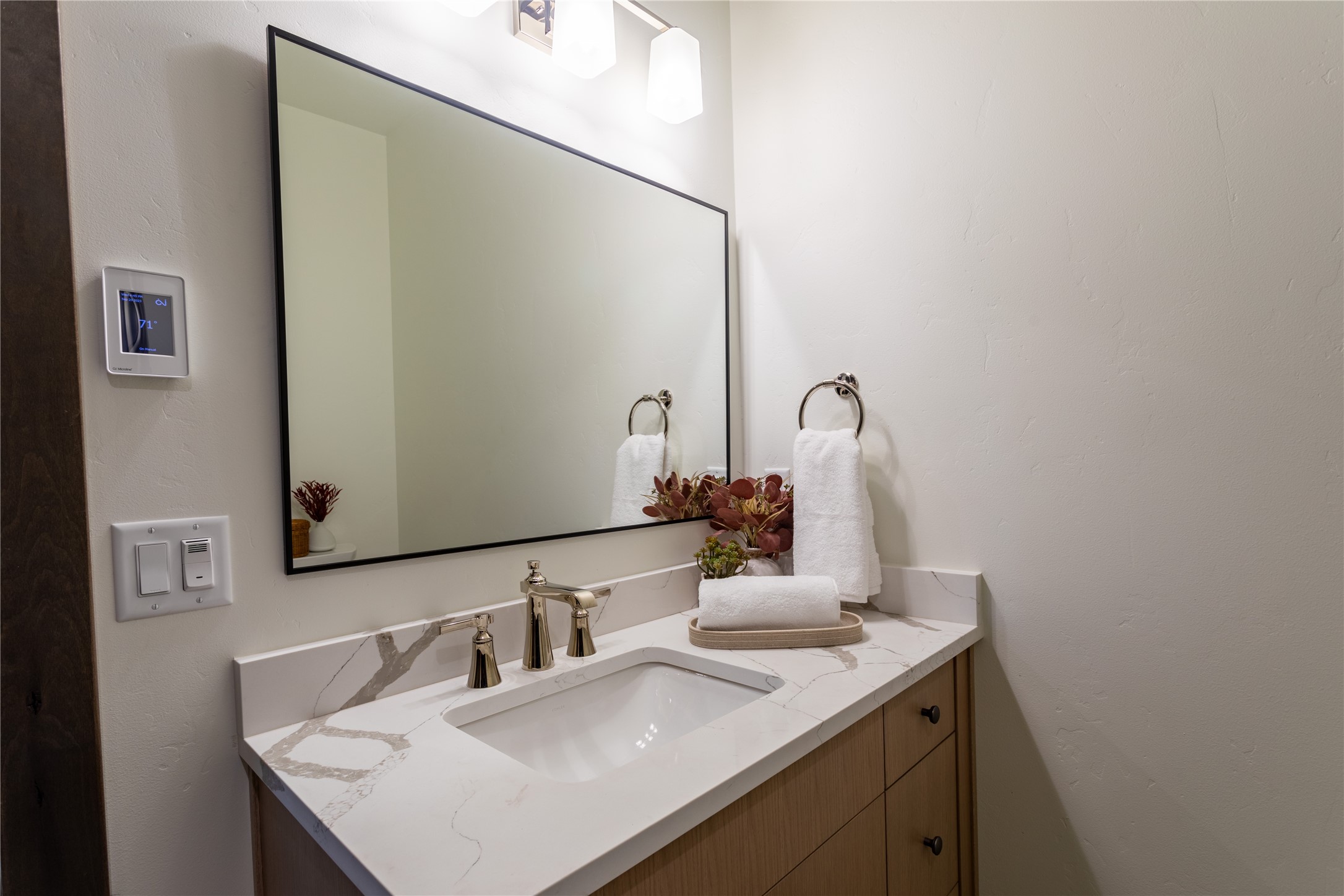 Bathroom vanity with a marble-look counter, integrated sink, black-framed mirror, and white towels.