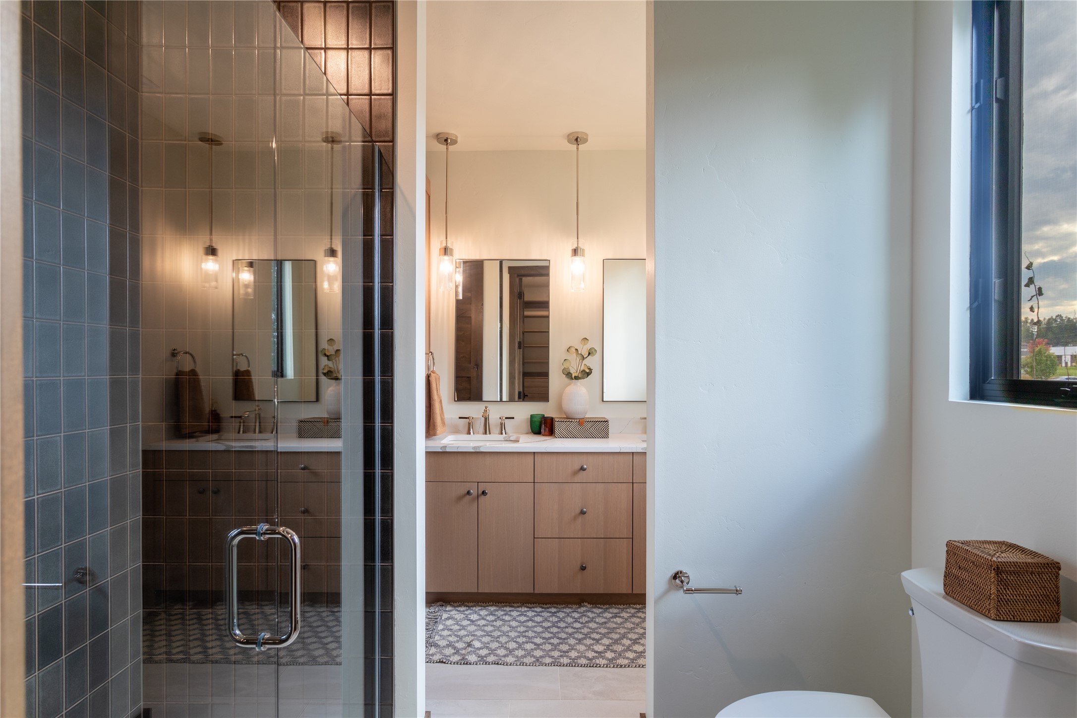 Modern bathroom with a dark tiled glass shower and wood double-sink vanity.