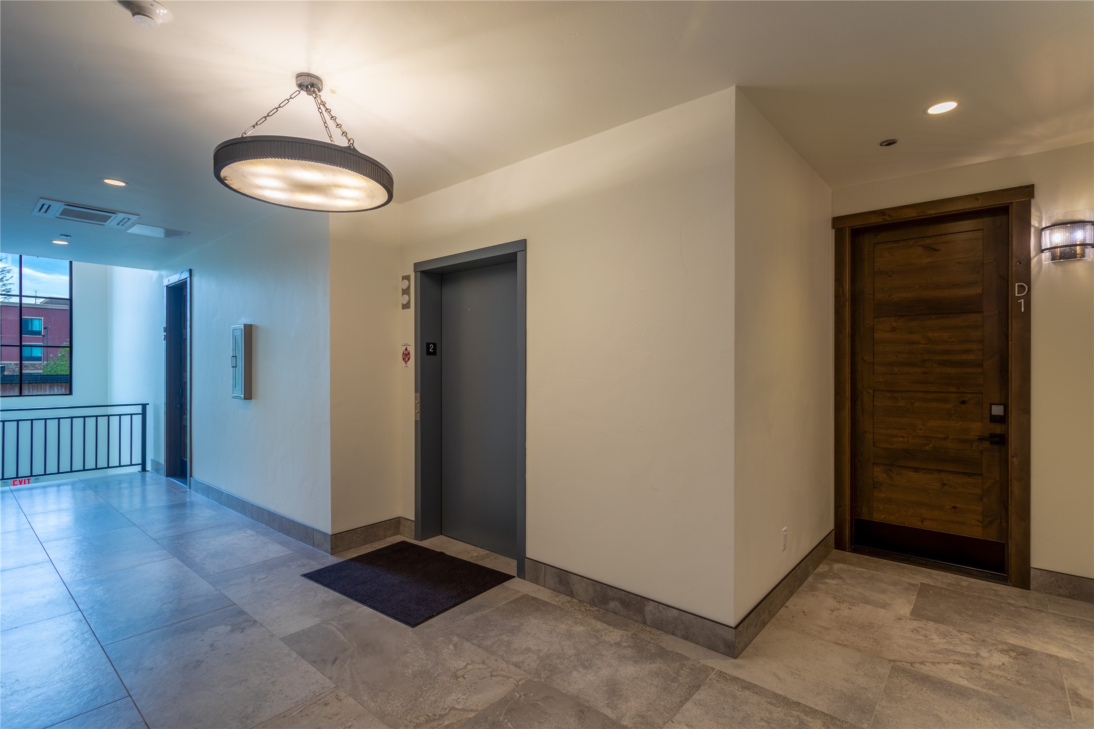Condominium hallway with a gray elevator and a dark wood door marked D1.