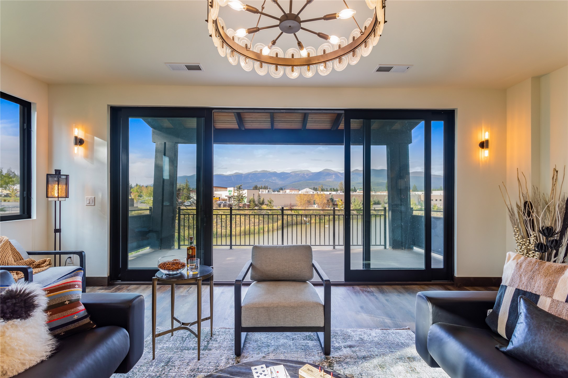 Furnished living room opening onto a balcony with water and mountain views.