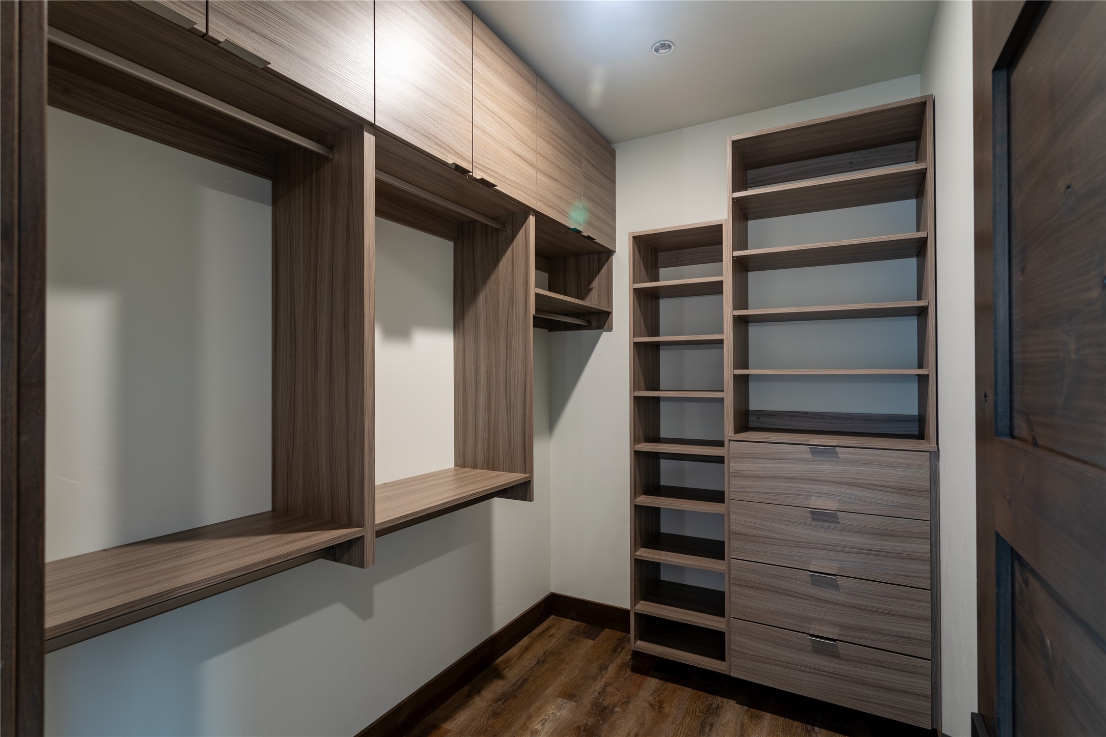 Walk-in closet with custom wood shelving, hanging space, and built-in drawers.