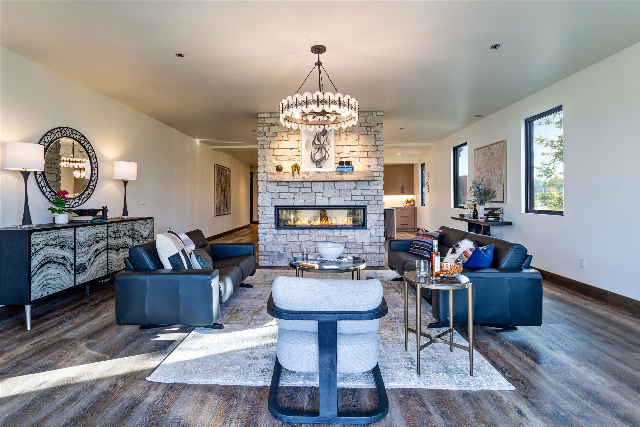 Living room with a stone fireplace, dark leather sofas, and large windows.