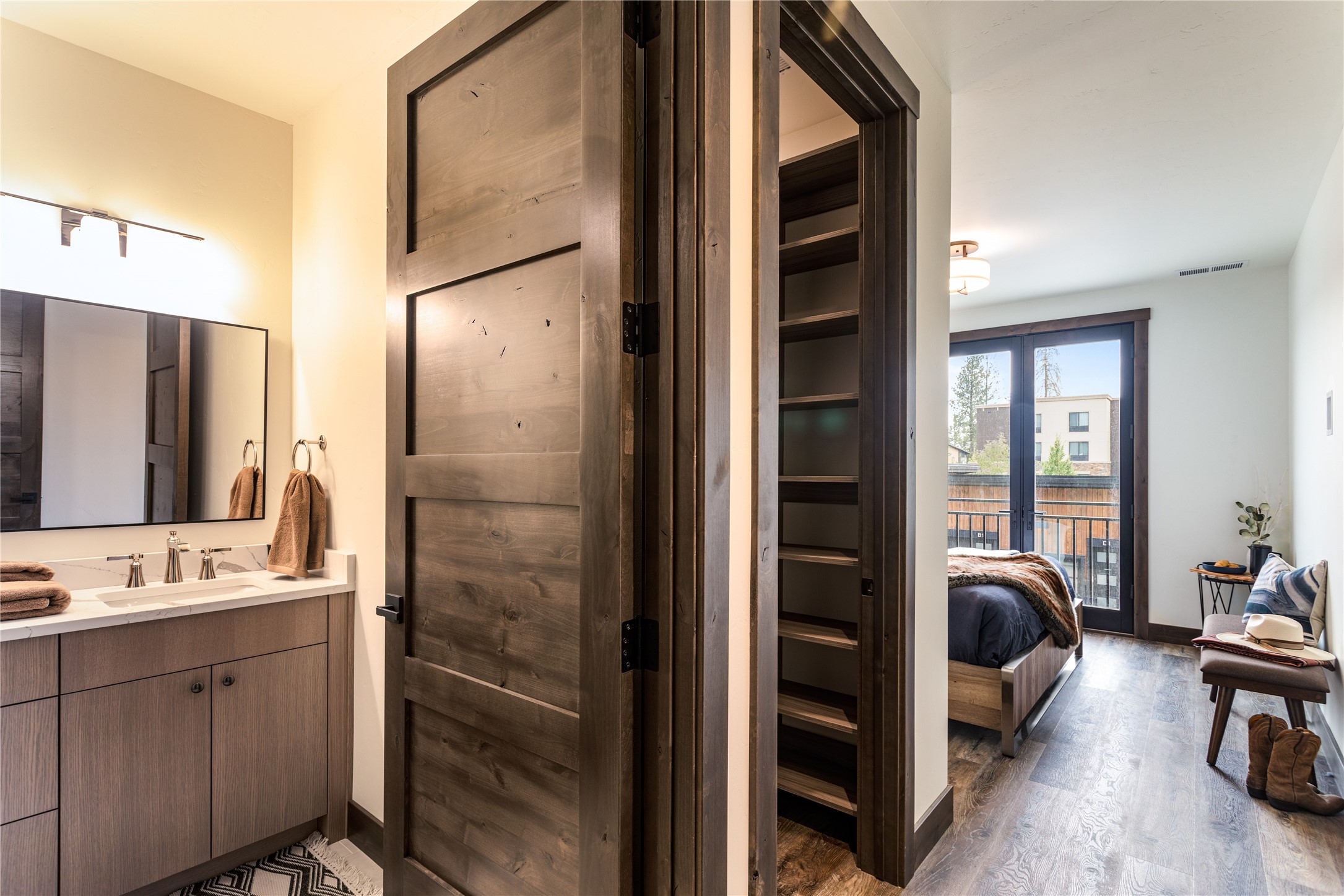 Bathroom and bedroom with a rustic wood door, built-in shelves, and balcony doors.