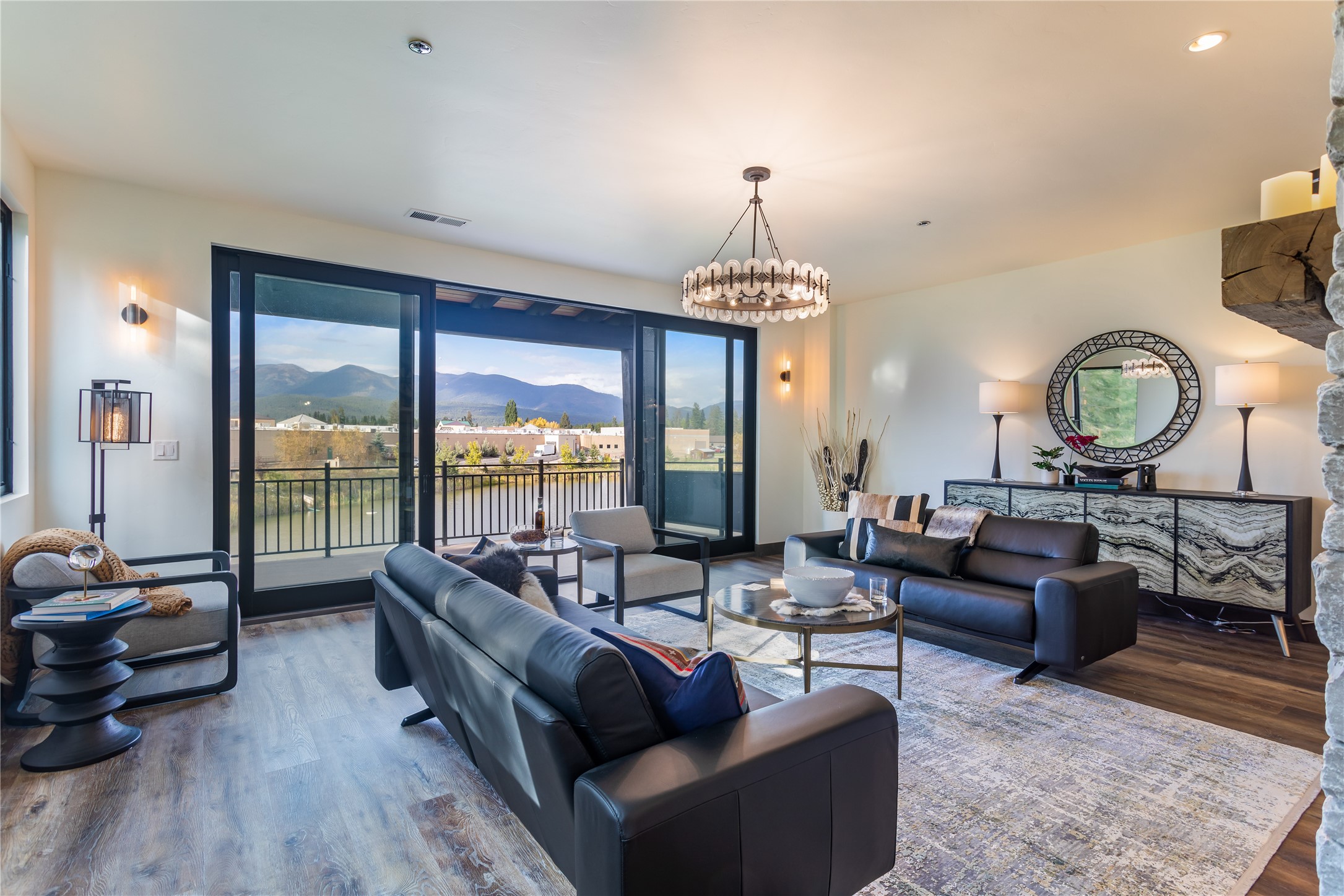 Furnished living room with leather sofas and sliding glass doors overlooking mountains.