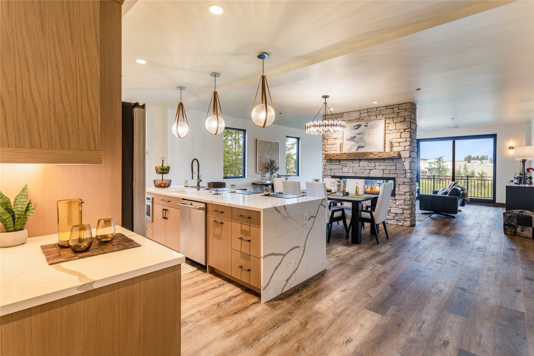 Open-plan kitchen and living area with a veined stone island and a stone fireplace.