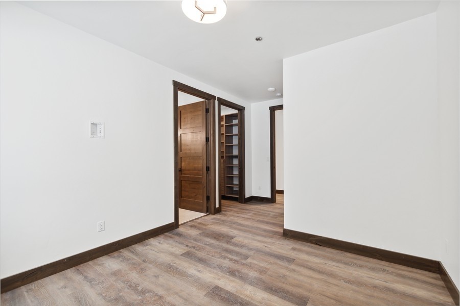 Empty room with wood-look flooring, dark trim, and a built-in bookshelf through the doorway.