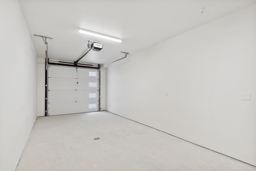 Empty white garage with a concrete floor and sectional overhead door.