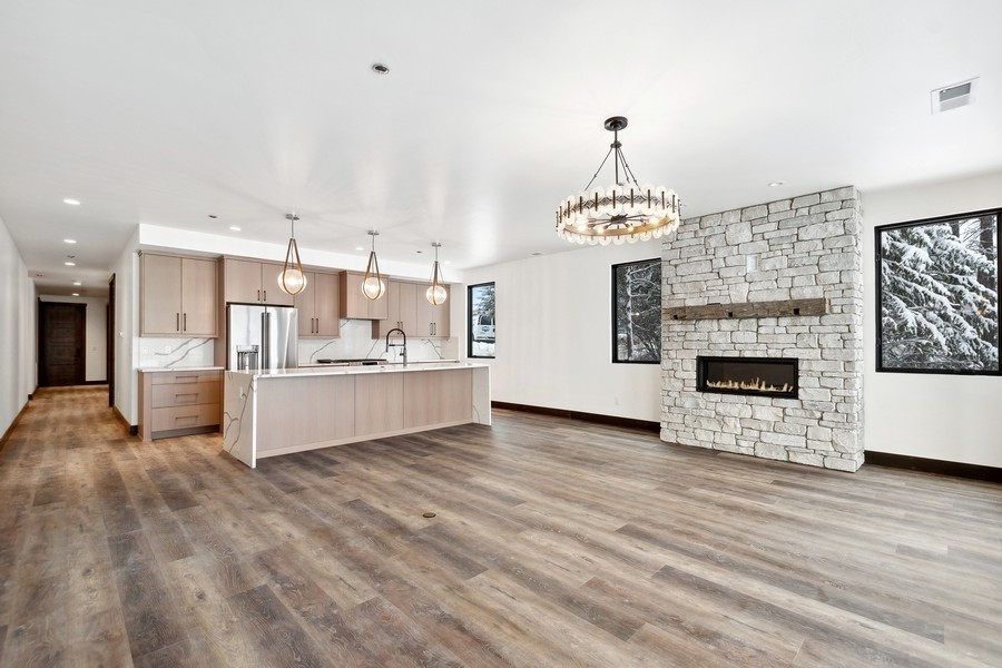 Open-plan kitchen and living area with a large island and stone fireplace.