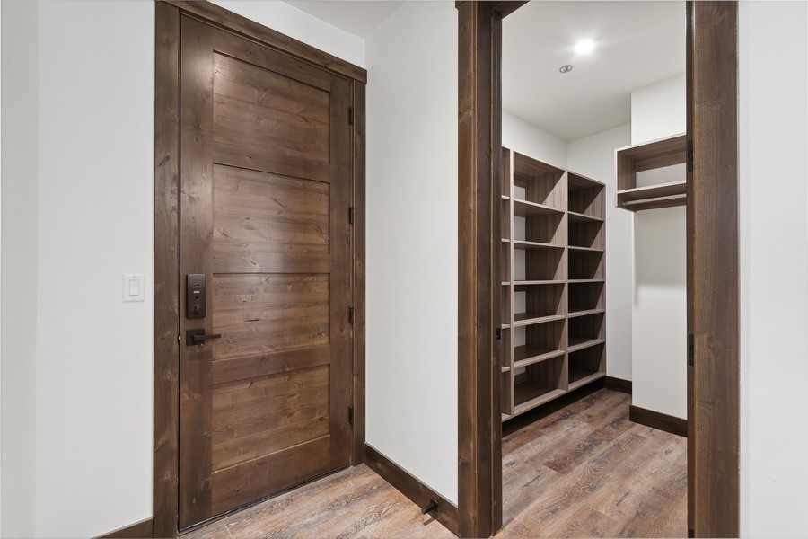 Walk-in closet with built-in dark wood shelving beside a rustic wood door.