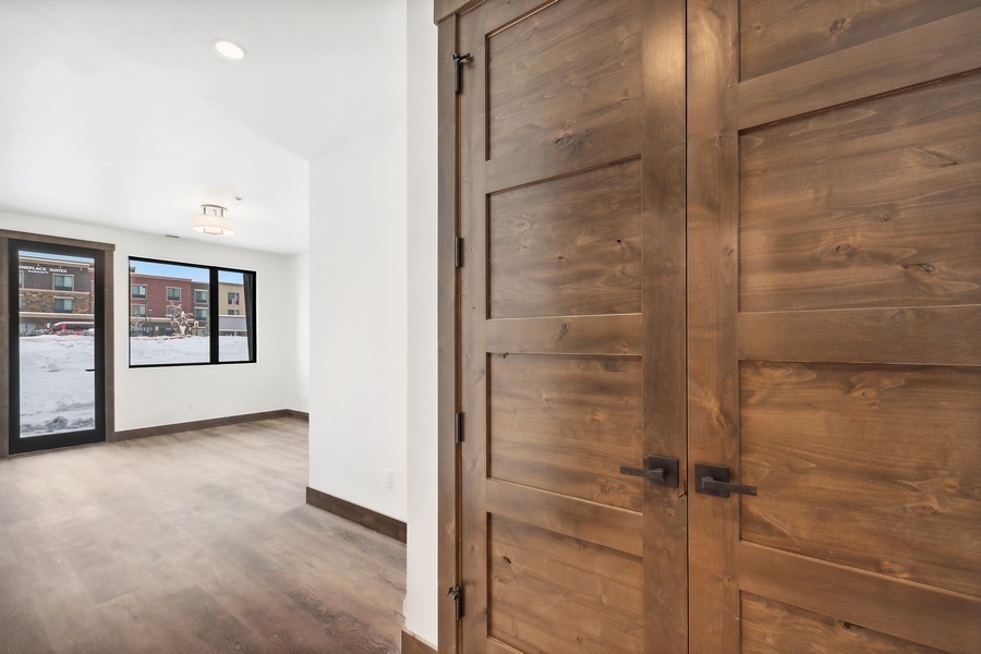 Vacant entryway with rustic wood double doors and windows overlooking snow.