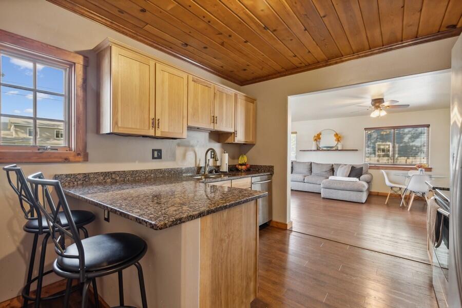 Kitchen with a granite breakfast bar and wood-plank ceiling, opening onto the living and dining area.