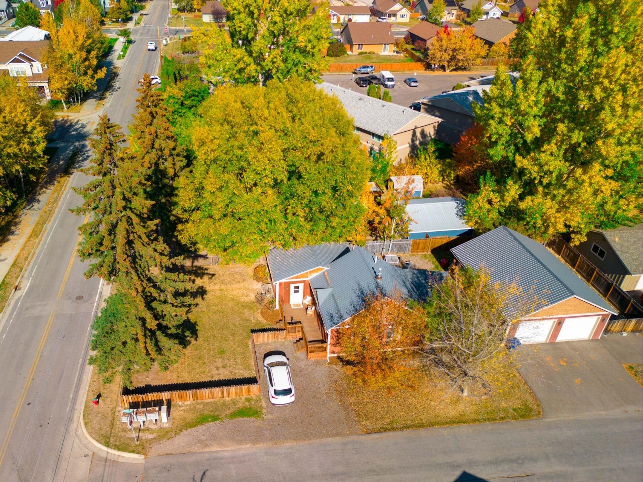 Aerial view of a corner-lot home with a detached garage and autumn trees.