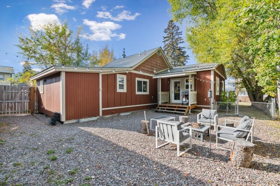 Red-sided house with a covered porch, gravel yard, and outdoor seating area.