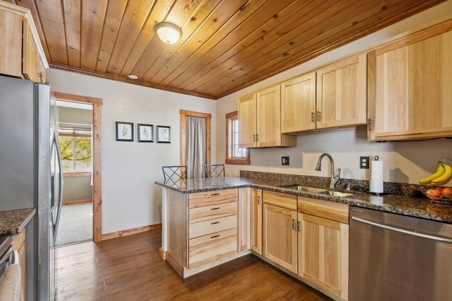 Kitchen with light wood cabinetry, granite counters, and a wood-plank ceiling.