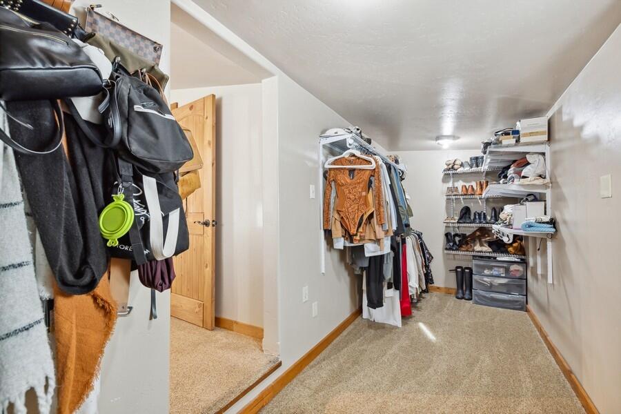 Walk-in closet with hanging clothes and shelves of shoes and storage bins.