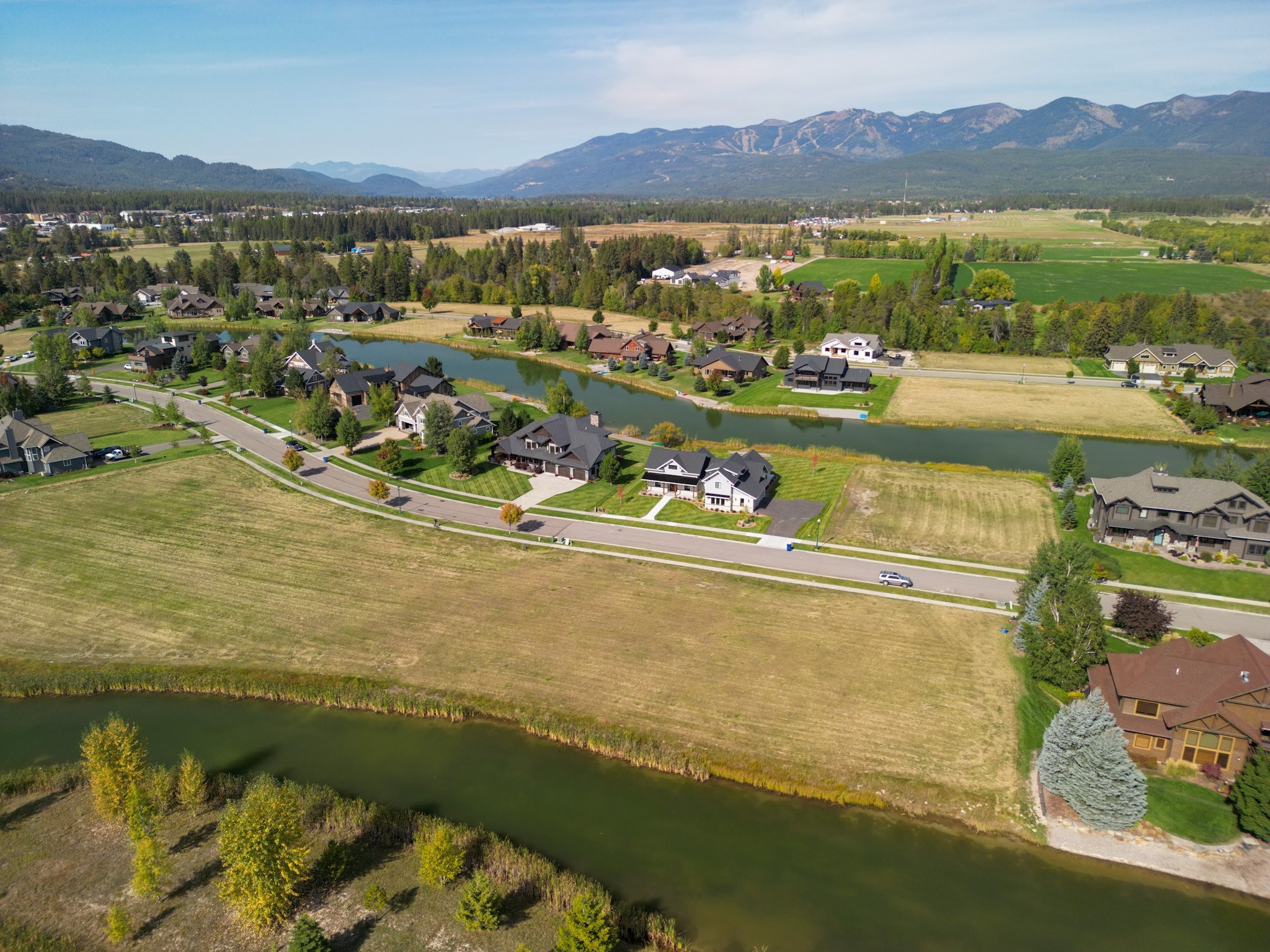 Aerial view of lakeside homes with a winding waterway and mountains beyond.