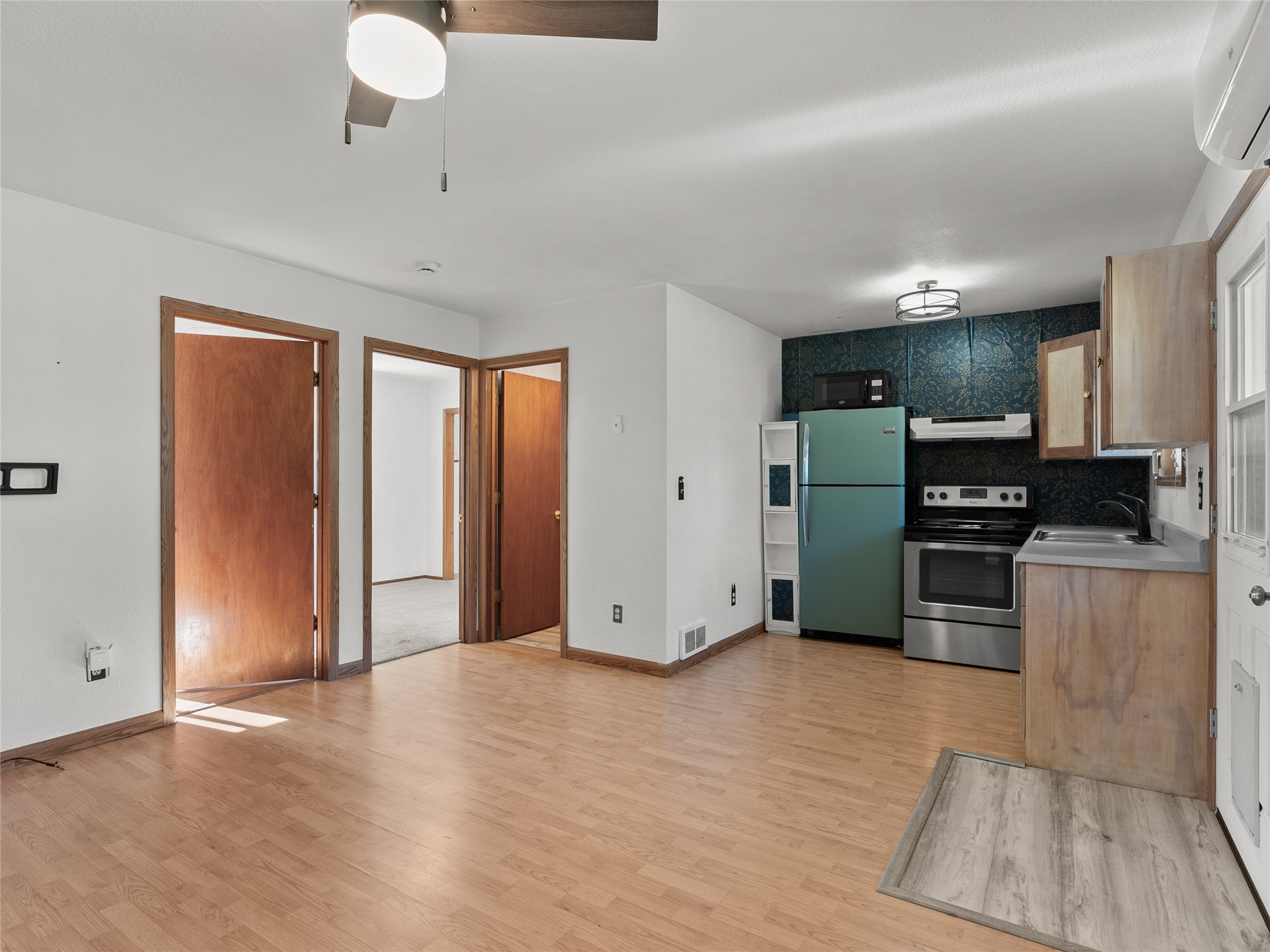 Kitchen with a teal refrigerator, stainless steel range, dark patterned backsplash, and adjoining open room.