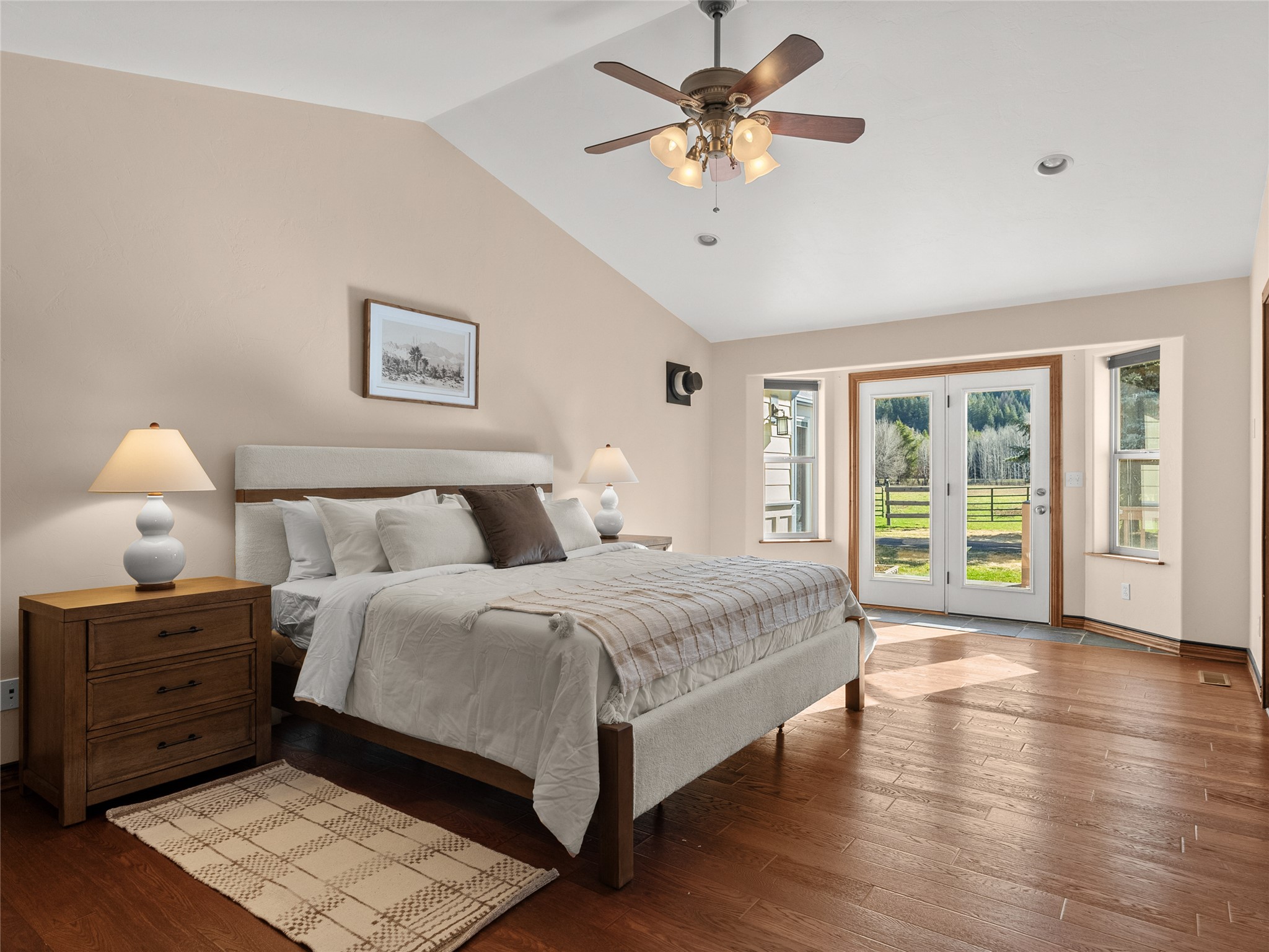 Furnished bedroom with a large bed and glass doors overlooking a fenced yard.