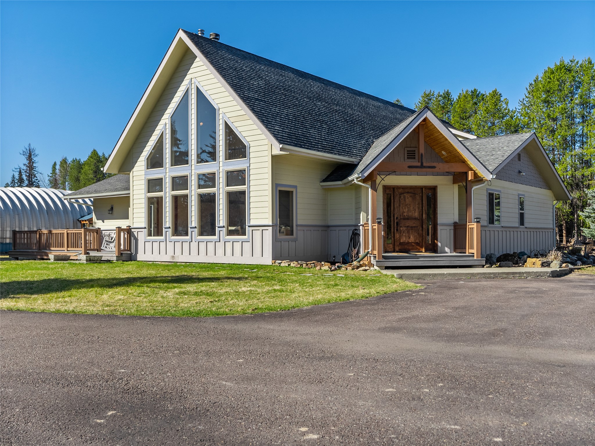 House with a tall wall of windows, covered timber entry, and wooden deck.