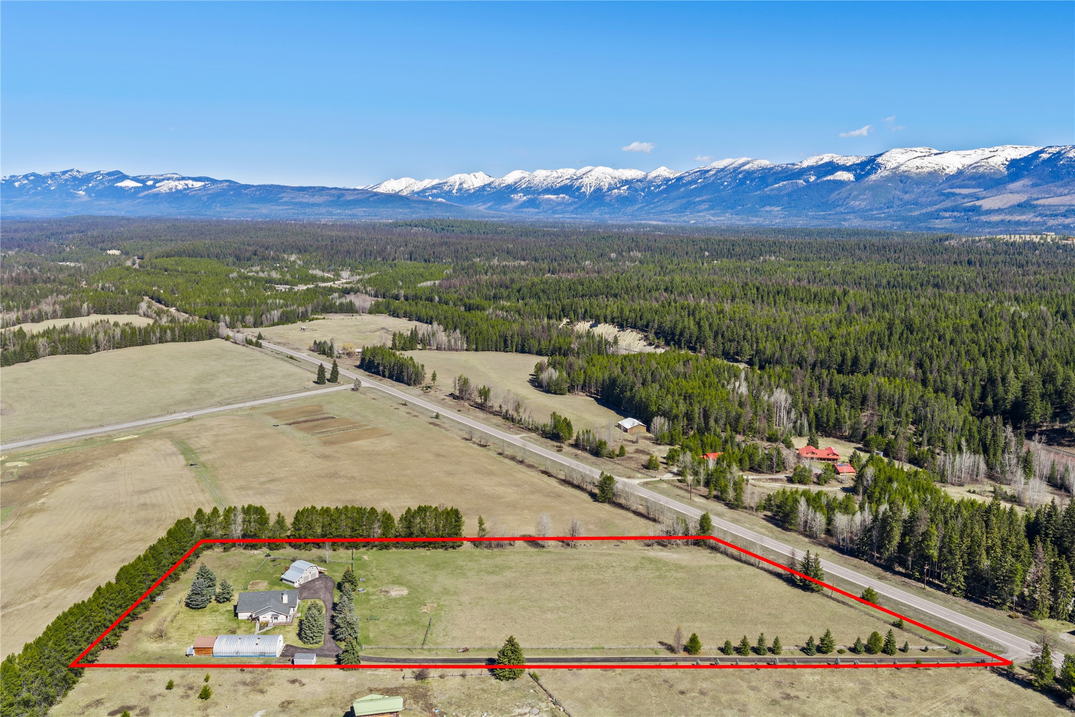Aerial view of a rural property outlined in red, with a house and outbuildings beside open pasture and a highway.