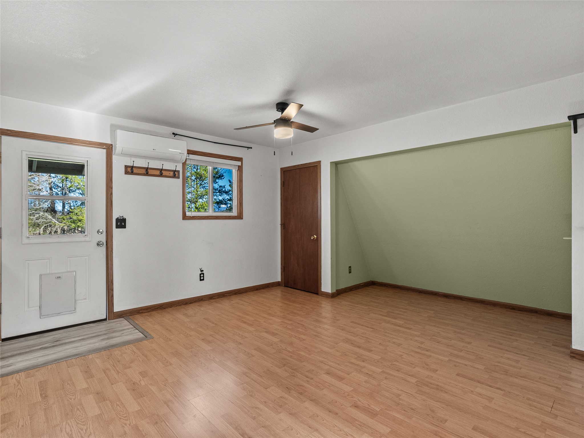 Unfurnished room with a sage-green recessed nook, wood floors, and ceiling fan.