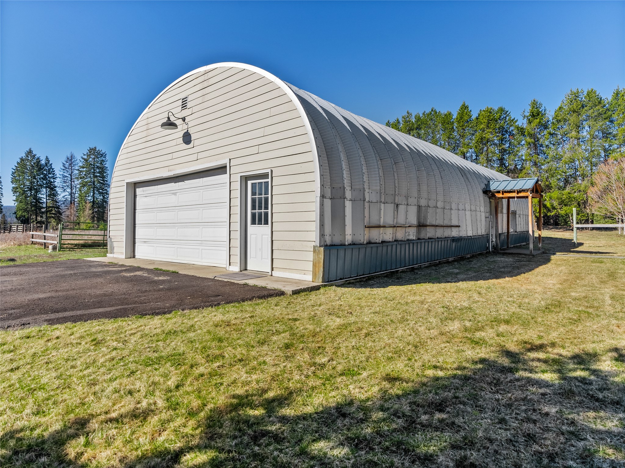 Arched-roof metal outbuilding with a large garage door and covered side entrance.