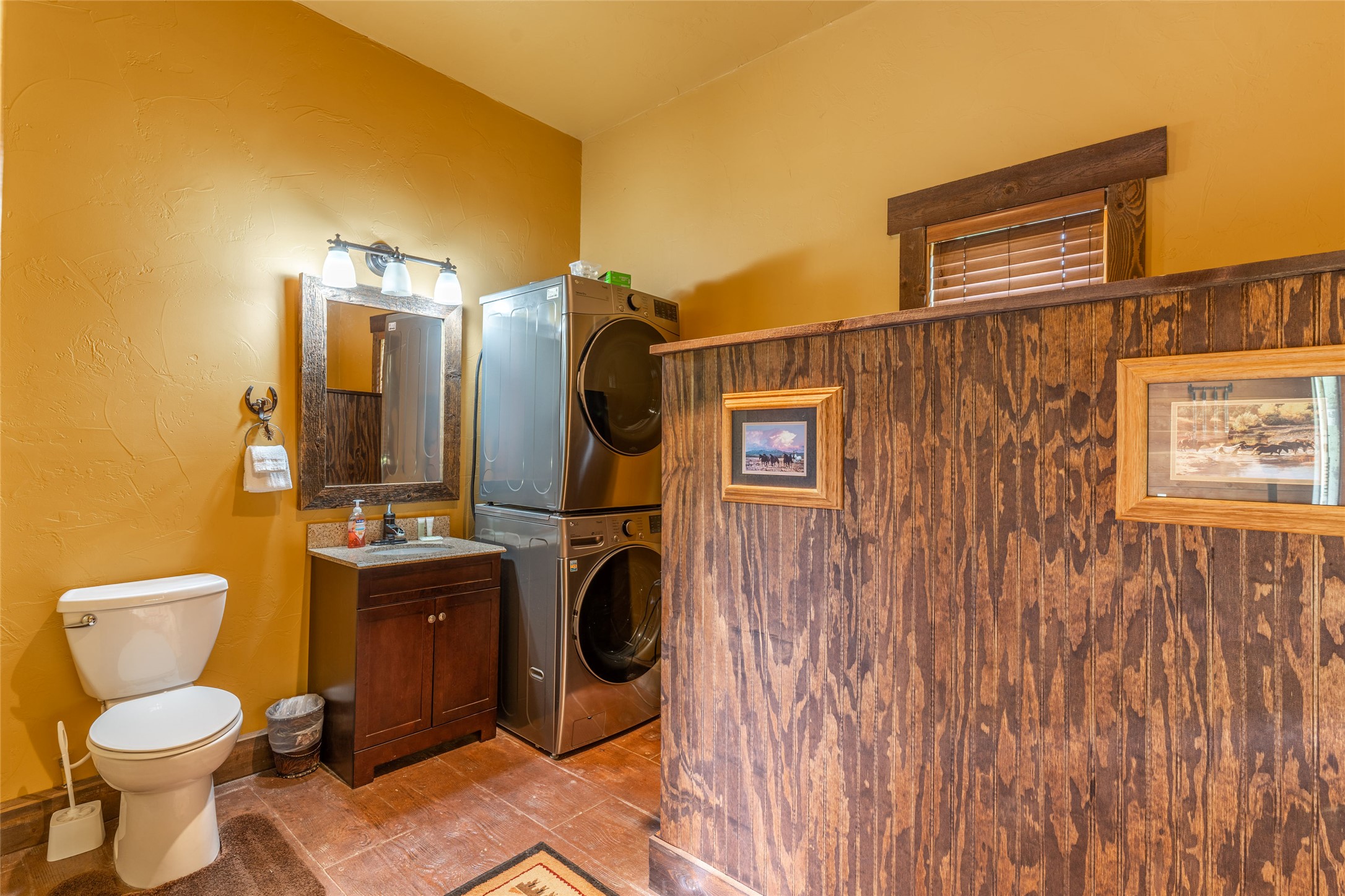 Bathroom and laundry area with stacked washer and dryer behind a rustic wood partition.