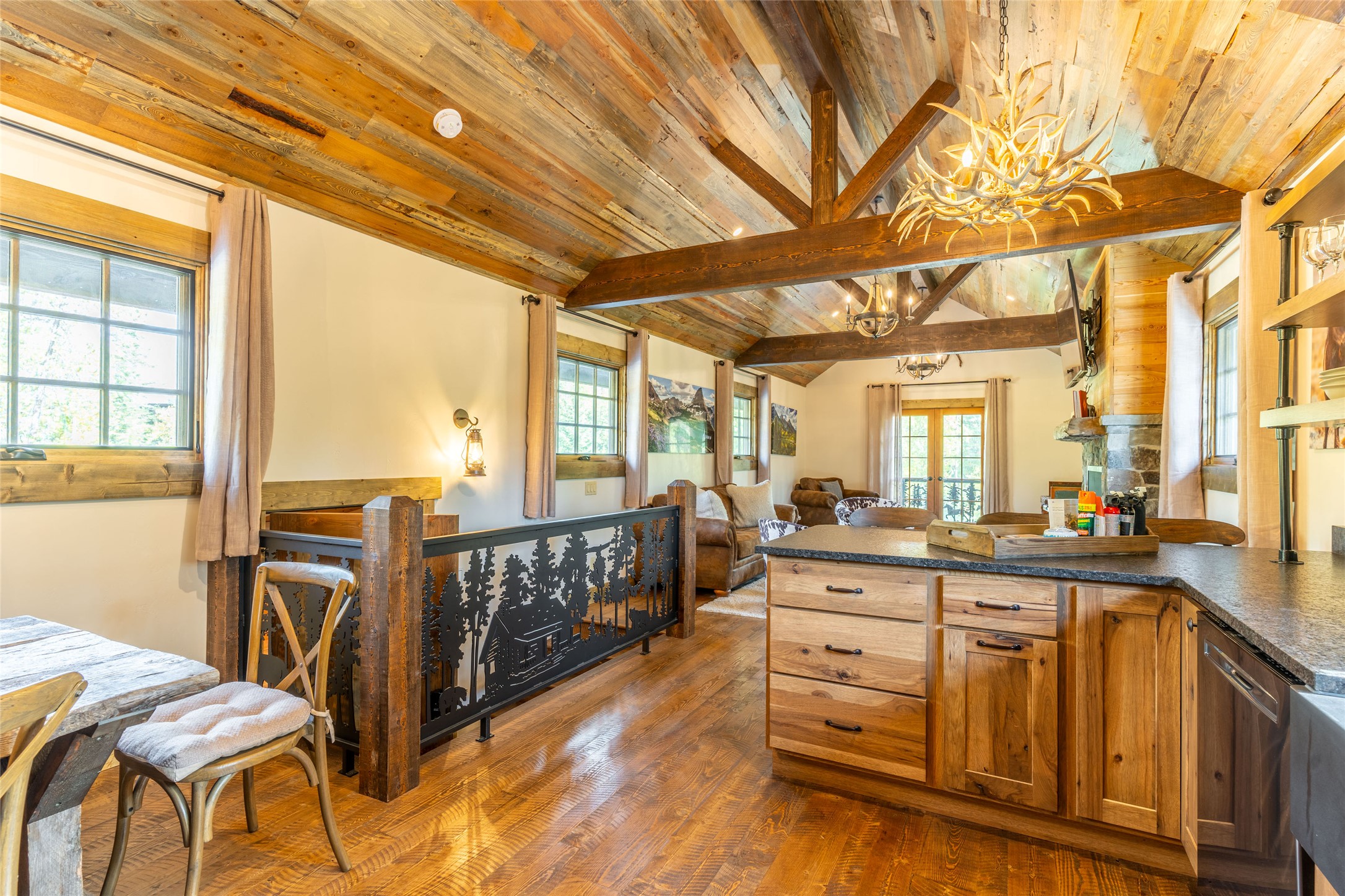 Open-plan kitchen and living area with a wood island, vaulted timber ceiling, and exposed beams.