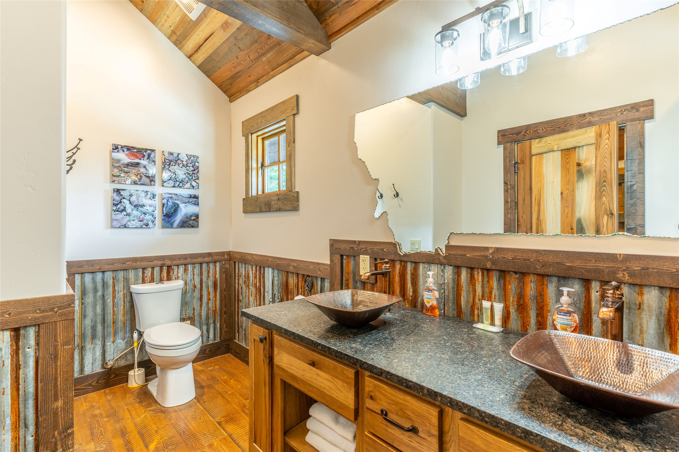 Bathroom with twin copper vessel sinks, a wood vanity, and rustic corrugated metal wainscoting.