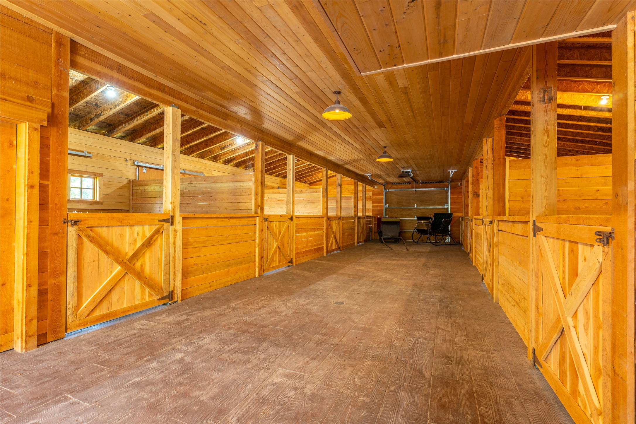 Wooden horse barn with rows of stalls and a wide central aisle.